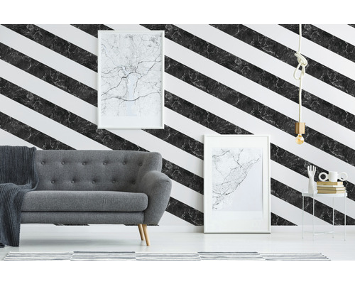 Salon avec un canapé gris devant un mur avec du papier peint à rayures diagonales