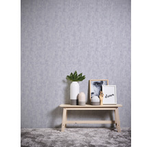 Dekoratives Arrangement mit Vasen, Bildern und Holzbank vor einer Wand mit Texturtapete.