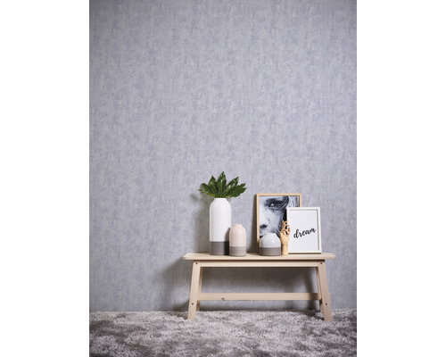 Dekoratives Arrangement mit Vasen, Bildern und Holzbank vor einer Wand mit Texturtapete.