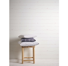 Raumansicht mit gemusterter Tapete, Hocker und Kissenstapel