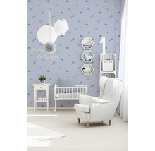 Kinderzimmer mit weißem Sessel, Babybett und blau gemusterter Tapete