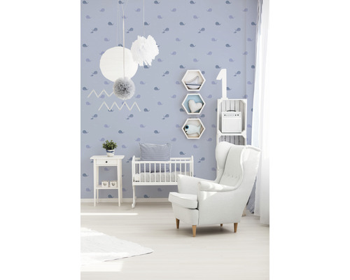 Kinderzimmer mit weißem Sessel, Babybett und blau gemusterter Tapete