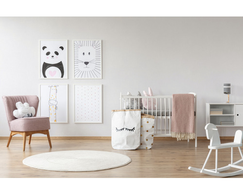 Helles Kinderzimmer mit Babybett, Sessel, Spielzeug, Teppich und Tierbildern an der Wand
