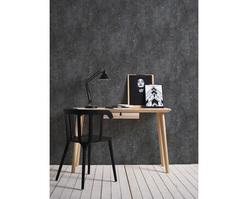 Arbeitszimmer mit Schreibtisch, Stuhl und Dekoration vor dunkler Wand