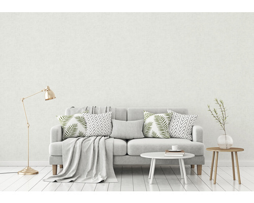 Wohnzimmer mit grauem Sofa, Kissen und Beistelltischen vor einer hellen Wand
