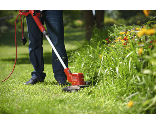 Person schneidet Gras mit einem Rasentrimmer
