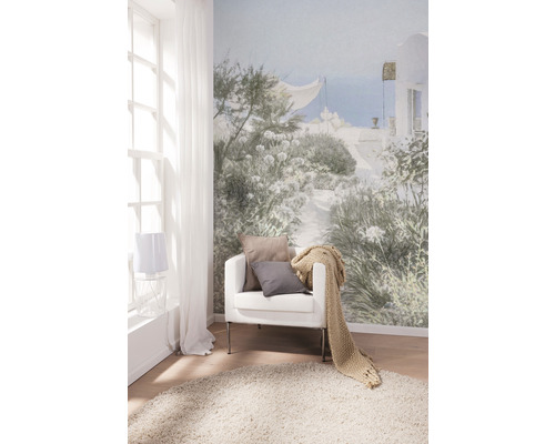 Salon avec papier peint photo, fauteuil, coussins, jeté de lit et tapis pour une ambiance claire et conviviale.