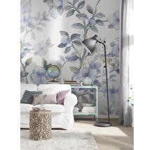Dekorierter Wohnraum mit Sofa, Beistelltisch und Stehlampe vor einer floralen Tapete