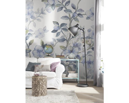 Salon décoré avec canapé, table d''appoint et lampadaire devant un papier peint floral