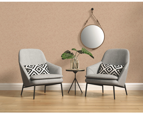 Zwei Sessel mit Kissen, ein runder Spiegel und ein Beistelltisch mit einer Vase und einer Pflanze in einem hellen Raum.