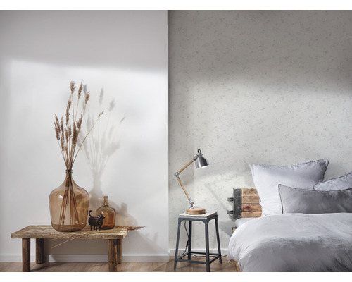 Helles Schlafzimmer mit gemusterter Tapete, Tischleuchte, Bett und Dekorationen