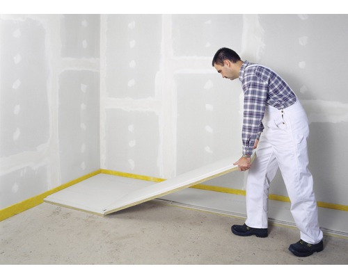 Mann verlegt Trockenbauplatten in einem Raum.