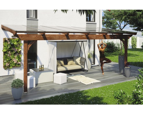 Toiture pour terrasses Skanholz Ravenna 648 x 250 cm, noyer Terrasse couverte avec structure en bois, mobilier de jardin et une personne pratiquant le yoga