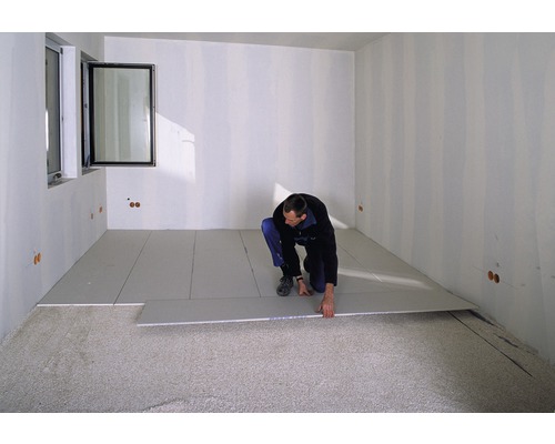 Ein Mann verlegt Trockenestrichplatten in einem Raum.