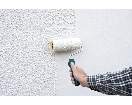 Eine Person streicht eine Wand mit einem Farbroller.