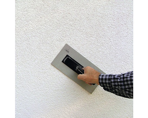 Hand mit Glättkelle beim Auftragen von Putz auf eine Wand