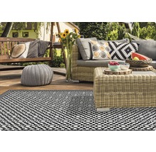 Terrasse avec mobilier en rotin, fauteuil suspendu et tapis d''extérieur à motifs.