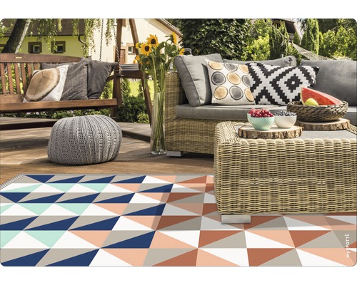 Outdoor-Szene mit geometrischem Teppich, Rattansofa und Holzelementen