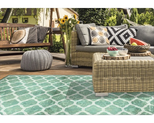 Gartenszene mit Rattansitzgruppe, Schaukel, Sitzhocker und gemustertem Teppich