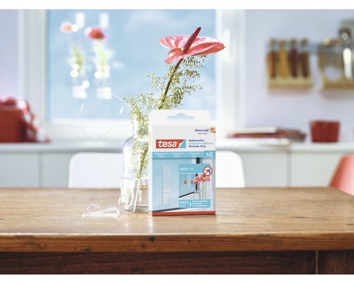 Paquet de bandes adhésives Tesa sur une table en bois avec des crochets et une fleur