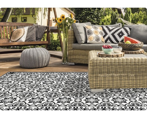 Dekorative Outdoor-Szene mit Rattanmöbeln und einem schwarz-weißen Teppich
