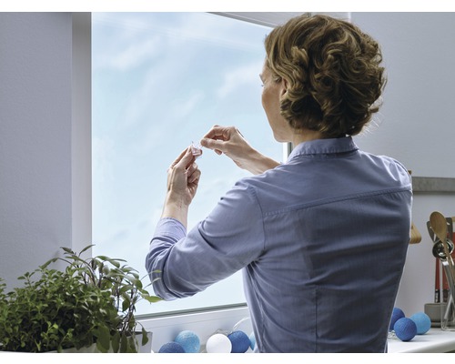Frau befestigt Fensterdekoration am Fenster