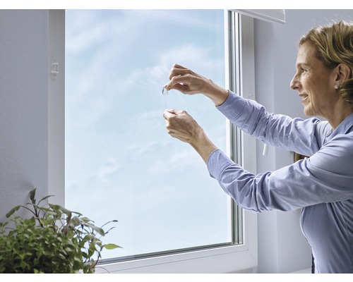 Frau bringt eine Fensterfolie an einem Fenster an