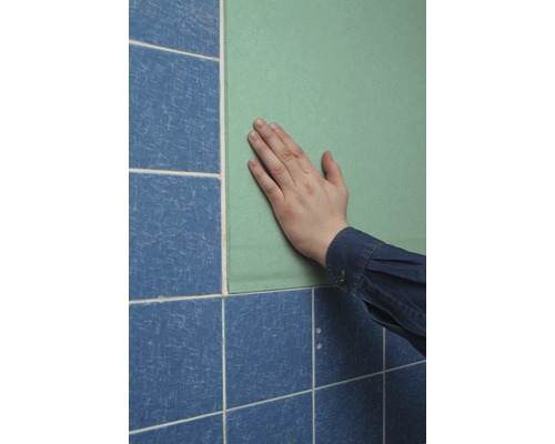 Hand auf einer Bauplatte neben blauen Fliesen