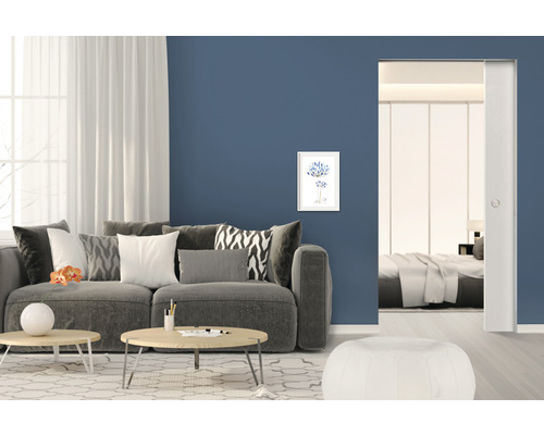 Salon avec canapé, table basse, tableau mural et porte coulissante vers la chambre à coucher.