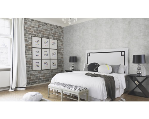 Chambre claire avec lit, tables de chevet, banc et papier peint mural en briques