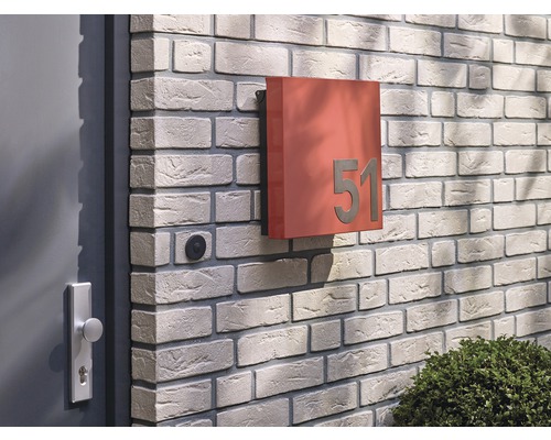 Quadratischer Briefkasten mit Hausnummer an einer Ziegelmauer