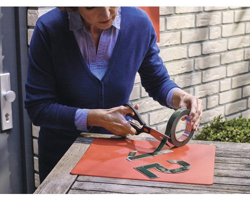 Frau schneidet doppelseitiges Klebeband mit einer Schere zu