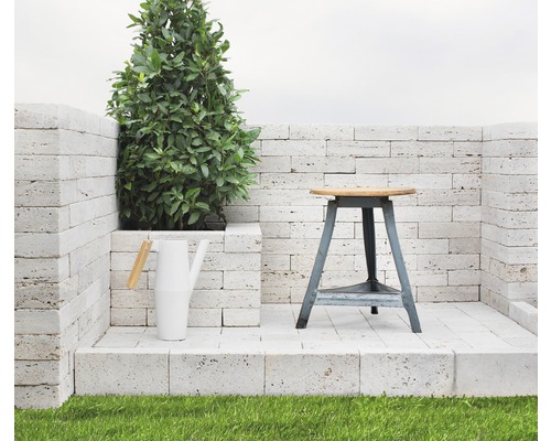 Scène avec une plante, un arrosoir et un tabouret sur une plateforme en pierre