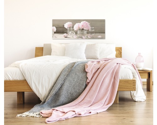 Chambre avec lit, couvertures et une image de fleurs