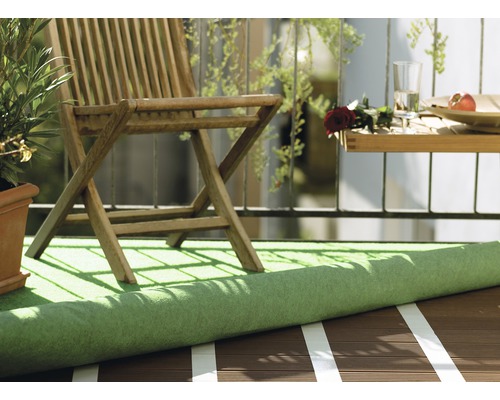 Scène de balcon avec gazon synthétique, chaise en bois et petite table