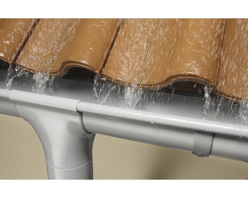 L''eau de pluie s''écoule du toit dans une gouttière en plastique.