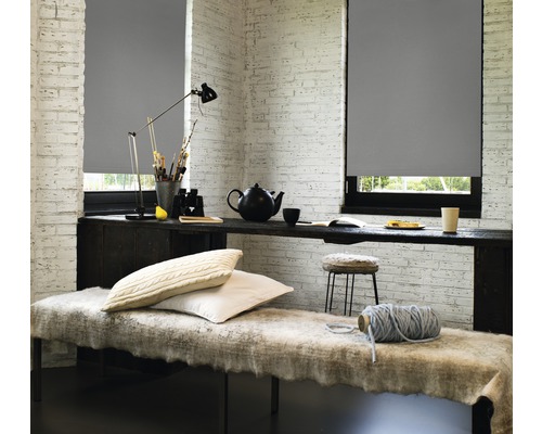 Pièce décorative avec stores enrouleurs gris aux fenêtres et une table avec divers objets.