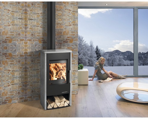 Salon avec poêle à bois, bûches et grande baie vitrée