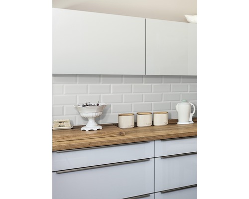 Küchenszene mit weißen Schränken, hölzerner Arbeitsplatte und weißen Fliesen