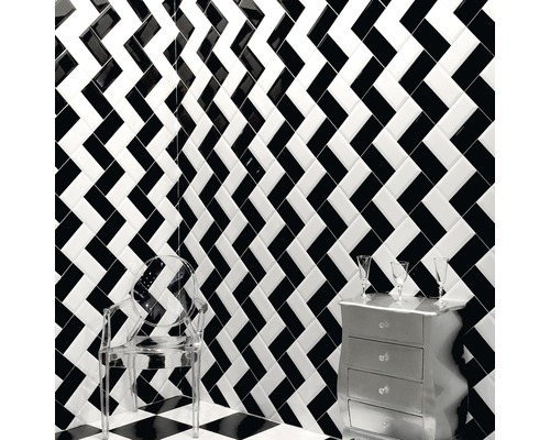 Raumansicht mit schwarz-weiß gemusterten Wand- und Bodenfliesen, transparentem Stuhl und Kommode