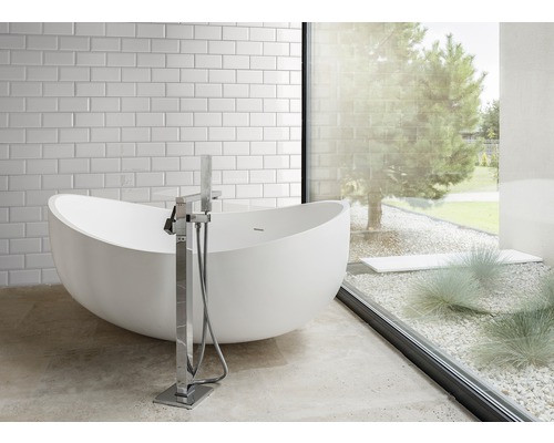 Badezimmer mit freistehender Badewanne, Armatur und Fenster zum Garten