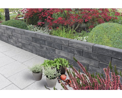 Aménagement paysager de jardin avec mur en blocs de béton et plantations