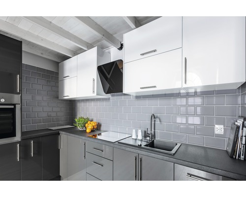 Moderne Küche mit grauen Fliesen, weißen und grauen Schränken sowie einer Dunstabzugshaube.