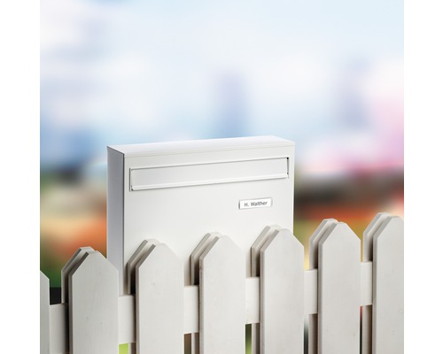 Briefkasten aus Stahlblech vor einem Gartenzaun