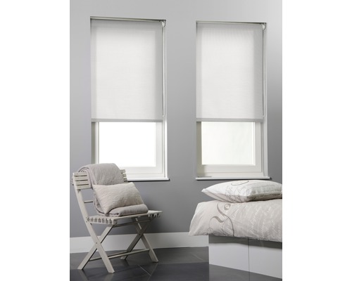 Deux stores enrouleurs blancs sur des fenêtres dans une chambre avec une chaise et un lit