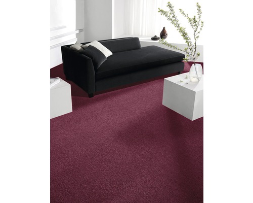 Innenraum mit dunkelrotem Teppichboden, schwarzem Sofa und weißen Möbeln