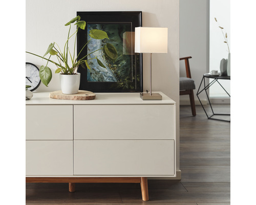 Commode avec décoration, lampe de table et image encadrée dans une pièce lumineuse