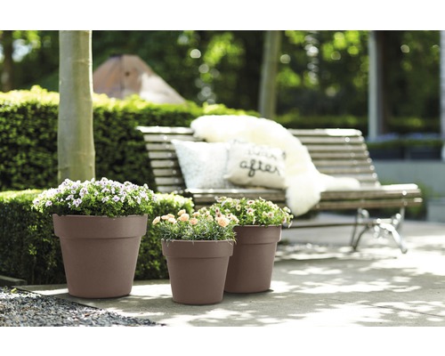 Drei braune Pflanzgefäße mit Blumen im Garten