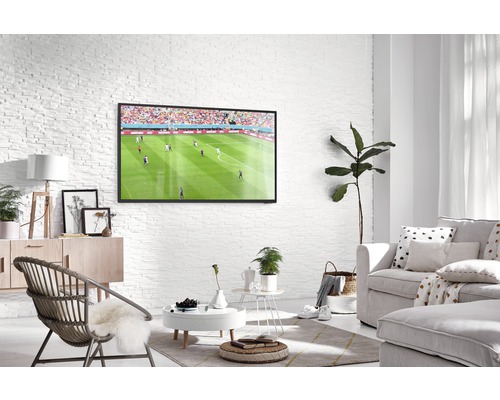 Helles Wohnzimmer mit Fernseher, Sofa und Sessel