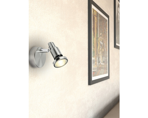 Wandleuchte aus Metall neben einem gerahmten Bild an einer Wand